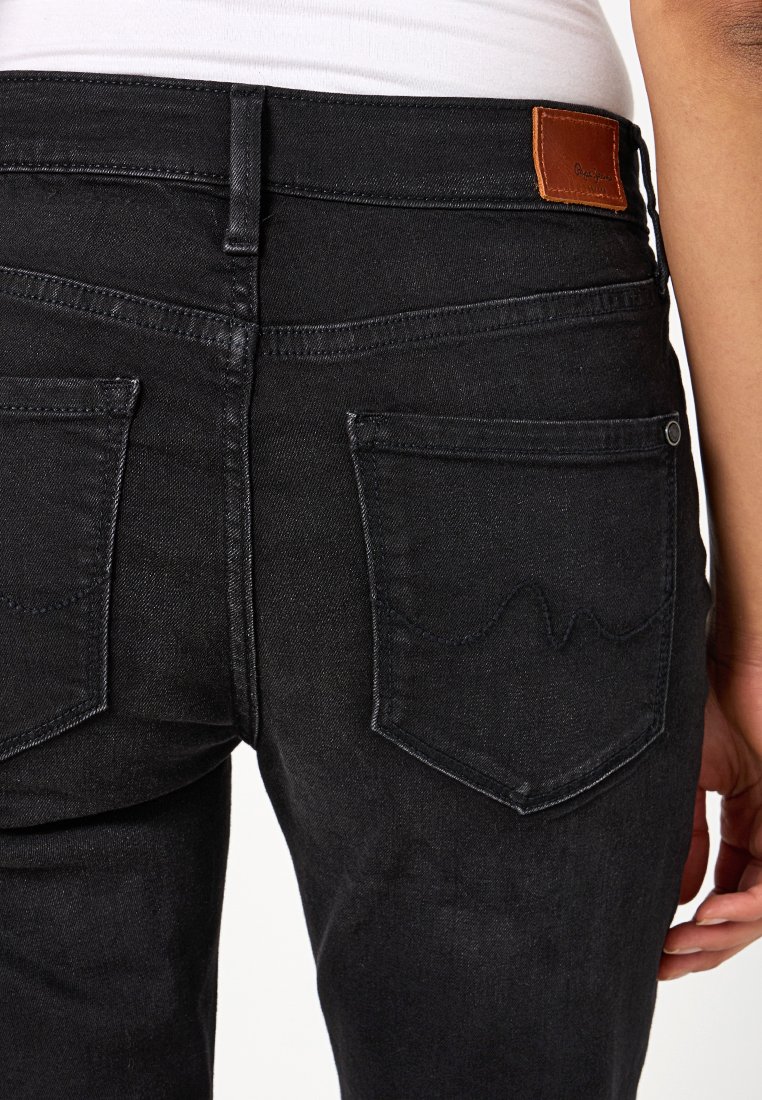 Jean en denim noir avec une taille mi-haute, deux poches arrière avec des coutures discrètes, et une étiquette en cuir à la taille.