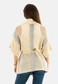 Cardigan beige in maglia con strisce grigie, trama a trama aperta, maniche ampie e vita con cintura. Presenta dettagli di piccole paillettes argentate.