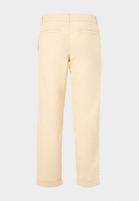 Lichtbeige broeken met een rechte voorkant, rechte pijpen en opgerolde boorden. Beschikt over twee achterzakken en minimale stikseldetails.