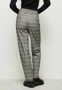 Grå rutig byxor med rak passform, subtil textur och bälteshällor, tillsammans med svarta klumpiga skor.