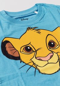 T-shirt blu con una grande grafica del volto del giovane Simba de Il Re Leone, concentrata sugli occhi espressivi e sui tratti del viso.