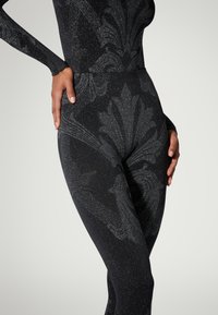 Body nera con finitura opaca caratterizzata da un motivo floreale testurizzato in grigio scuro, rifinita con sottili brillanti metallici.