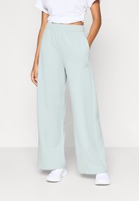 Ljusblå vida mjukisbyxor i mjukt material med elastisk midja och en liten logga på vänster höft.