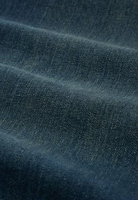 Granatowy materiał denim o gładkiej fakturze, z subtelnymi różnicami w odcieniu i drobnym splotem. Widoczny wzór ukośny w całym materiale.