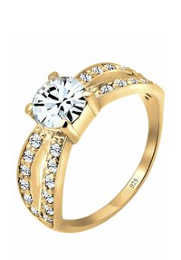 Gold ring featuring a large round clear gemstone at the center, surrounded by smaller crystals along the band with a smooth finish.