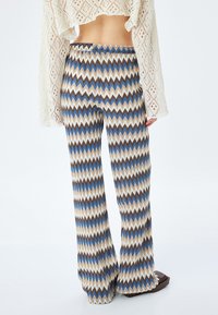 Patroon flared broek met een zigzagdesign in crèmekleurig, bruin en blauw. Elastische tailleband. Gemaakt van een gestructureerde breimaterialen.