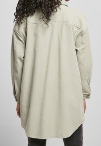 Ljusgrön kord skjorta med långa ärmar, en ryggsömn, och en avslappnad passform, med en böjd nederkant och subtil texturerad detaljering.