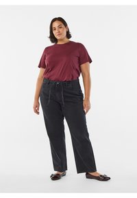 Bordeauxrød bomulds-T-shirt kombineret med højtaljede sorte denimjeans. Skoene er skinnende bordeaux med dekorative hardware-detaljer.