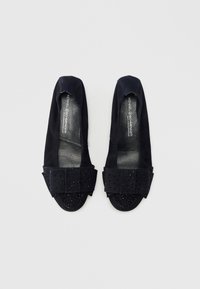 Μαύρα σουέντ μπαλαρίνες με στρογγυλερή μύτη, διακοσμημένες με υφασμάτινο φιόγκο με υφή και καρφιά στο καπάκι της μύτης. Λείος εσωτερικός επένδυση.