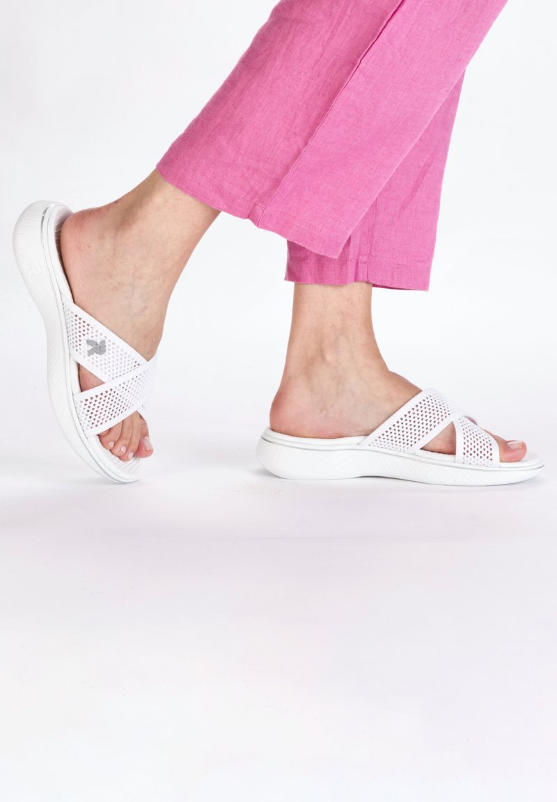 White sandals with a cross-strap design, made of perforated material. The sole is textured and slightly cushioned for comfort.
