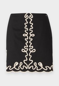 Jupe noire avec un motif brodé texturé de couleur crème, comprenant des motifs en spirale sur le devant et le long de l'ourlet.