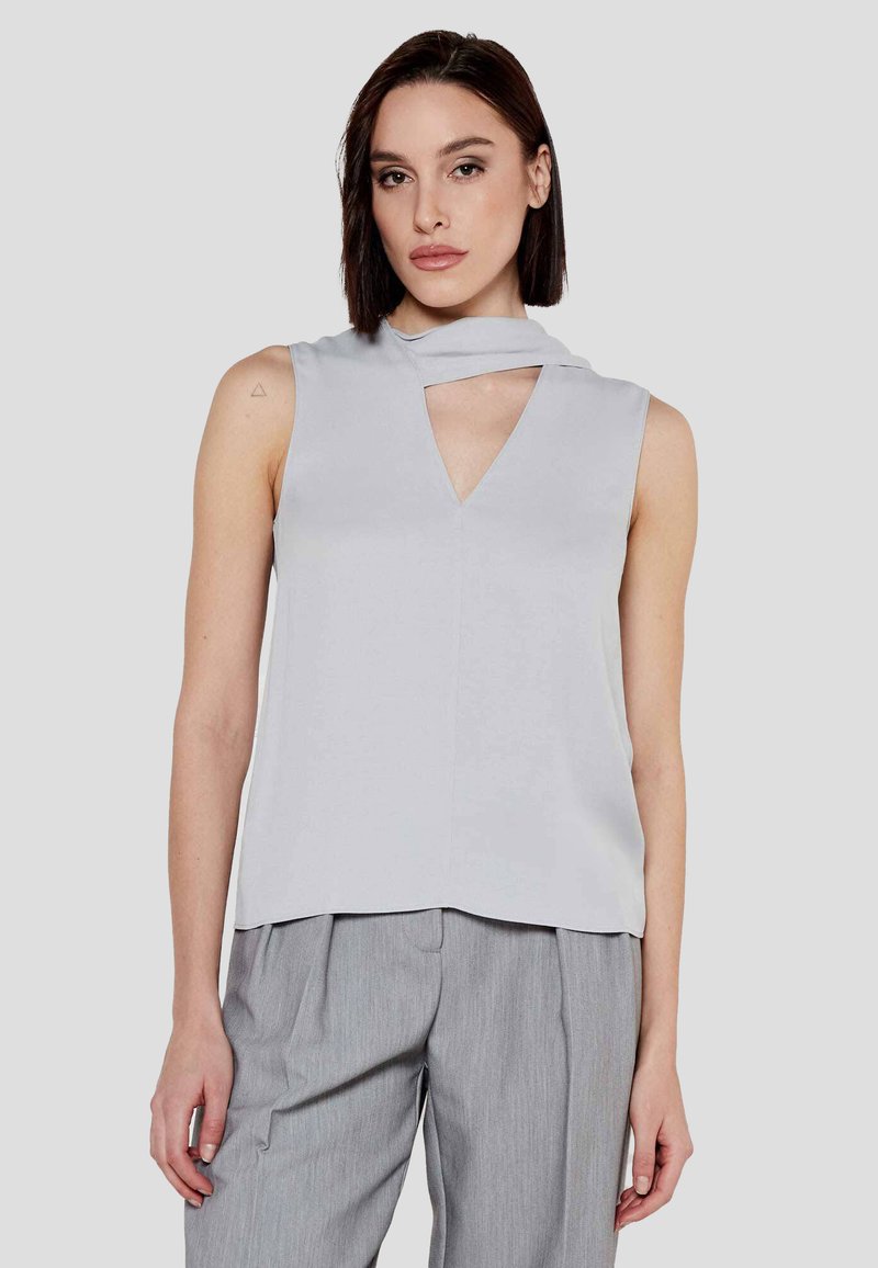 Top senza maniche grigio chiaro con scollatura a V e scollatura asimmetrica. Texture liscia con vestibilità morbida, caratterizzato da un sottile dettaglio di taglio.