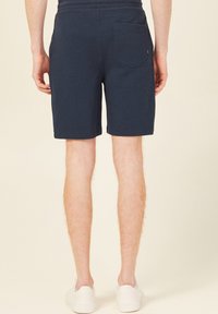 Granatowe bawełniane szorty z tylną kieszenią, o prostym kroju i długości kończącej się powyżej kolana. Gładka faktura, elastyczny pas.