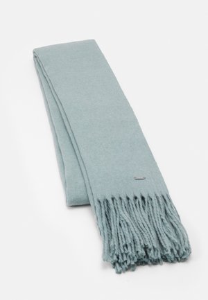 Écharpe bleue claire pliée avec des extrémités à franges torsadées et une petite étiquette de marque métallique rectangulaire sur un côté.