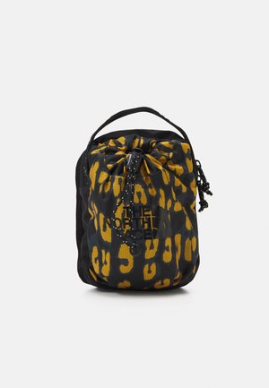 Kompaktní pytlíček se šňůrkovým zavíráním, vzor černých a žlutých leopardích skvrn, horní ucho a černý text loga na přední straně.