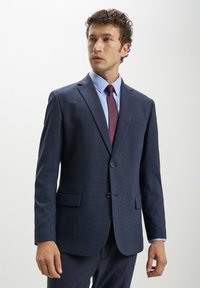 Abito blu navy con un motivo testurizzato, design a un bottone, rever a V e pantaloni abbinati. Include una camicia azzurro chiaro e una cravatta bordeaux.