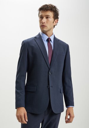 Abito blu navy con un motivo testurizzato, design a un bottone, rever a V e pantaloni abbinati. Include una camicia azzurro chiaro e una cravatta bordeaux.