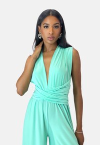Mono verde menta con escote en V profundo y detalle de cintura envuelta. Tela suave y ligera con piernas de pantalón amplias y diseño sin mangas.