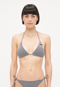 Svart og hvit ruter bikini med trekantet topp og justerbare snorer i sidene av trusen. Glatt stoff, minimal maskindetalj.