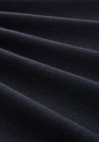 Tela negra con un tejido texturizado, que presenta suaves pliegues y un ligero brillo. La superficie es lisa, mostrando variaciones de color profundas y ricas.