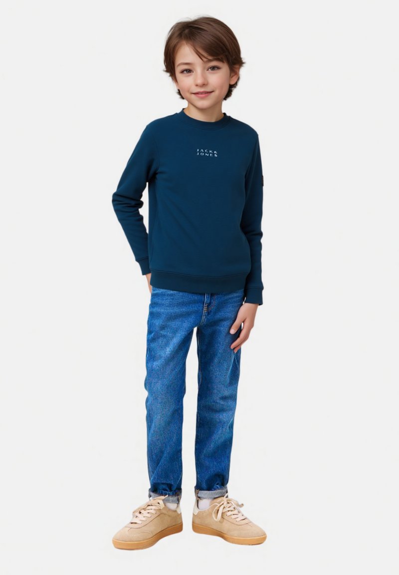 Felpa navy con logo, jeans blu e sneakers beige. Tessuto liscio, vestibilità comoda, maniche lunghe e orli dei pantaloni rifiniti. 