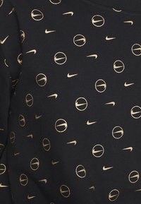 Czarna tkanina z powtarzającym się wzorem złotych logo Nike i okrągłych elementów. Miękka tekstura o swobodnym designie, odpowiednia do odzieży sportowej.