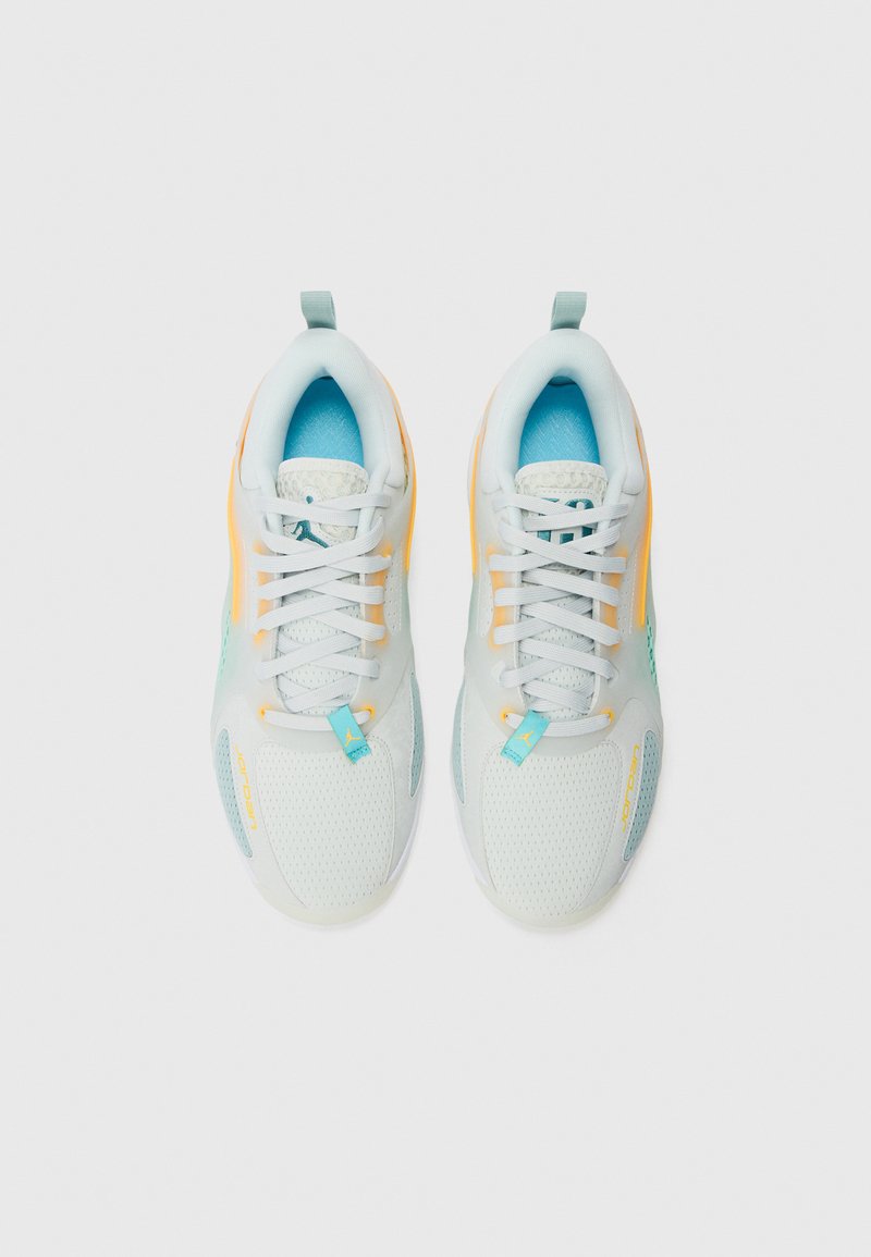 Zapatillas ligeras con una parte superior de malla blanca, acentos en azul aqua, detalles amarillos y cordones. Cuenta con una plantilla texturizada y superposiciones en los paneles.