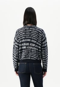 Strikket genser i marineblått med gjentatt hvit "JOOPJEANS" logo-mønster, rund hals, ribbestrikkede mansjetter og kant. Behagelig tekstur, avslappet passform.
