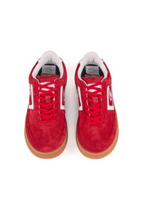 Sneakers in suede rosso con accenti bianchi, caratterizzati da una punta tonda, suola piatta in gomma e lacci coordinati. Il design include dettagli del logo sui lati.