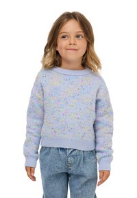 Jasnoniebieski sweter z dzianiny z kolorowymi kropeczkami, okrągłym dekoltem i ściągaczami. Połączony z luźnymi dżinsami.