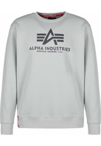 Felpa grigia chiara con collo girocollo, polsini e orlo a coste. Presenta un logo nero prominente e la scritta "ALPHA INDUSTRIES."