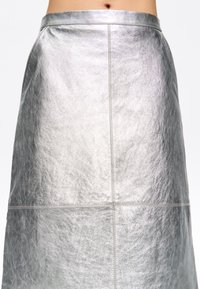 Zilveren leren rok met een gladde, glanzende textuur. Heeft een aansluitende taille en een rechte silhouet, waarbij de strakke stikseldetails worden benadrukt.