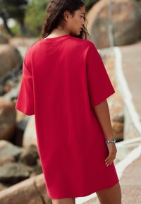 Rode, oversized t-shirt jurk met korte mouwen en een ontspannen pasvorm. Gladde stof, ronde halslijn, valt boven de knie. Eenvoudig ontwerp.