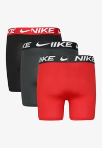 Muške bokserice Nike u pakiranju od tri komada, u crnoj, sivoj i crvenoj boji. Svaki par ima široki elastični pojas s bijelim Nike logotipom.