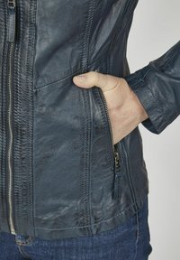 Marineblaue Lederjacke mit einem Reißverschluss vorne, seitlicher Tasche, dekorativen Nähten und einer glatten Textur. Taillierte Passform.
