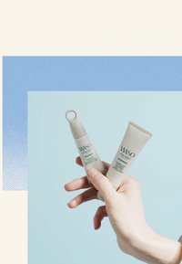 Due prodotti per la cura della pelle Shiseido WASO in tubi morbidi e arrotondati; uno è beige con un tappo circolare, l'altro è un tubo di crema con una texture rigata.