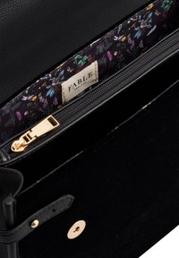 Black leather and velvet handbag with gold hardware. Interior features a floral patterned fabric and a zippered compartment. Brand label visible.