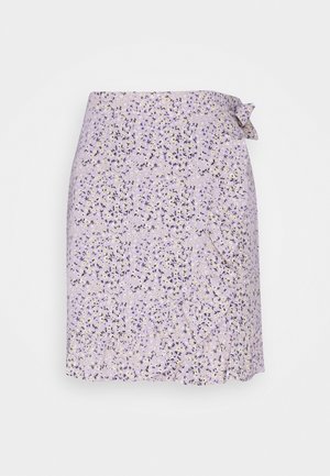 Falda envolvente lavanda con pequeño estampado floral en blanco y negro y detalle de lazo atado en la cintura.