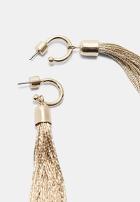 Orecchini dorati con lunghi e testurizzati frange metalliche. Il design include un cerchio e una chiusura a perno con accenti lisci.
