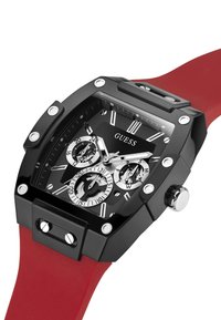 Schwarze rechteckige Uhr mit rotem Silikonarmband, silbernen Akzenten und mehreren Zifferblättern. Sie verfügt über auffällige Stundenmarkierungen und ein strukturiertes Gehäuse.