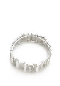 Pulsera de plata que presenta piezas curvadas entrelazadas, textura suave y un acabado pulido, diseñada para ajustarse cómodamente a la muñeca.