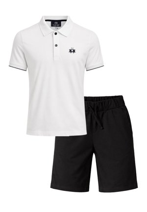 Polo bianca a maniche corte con logo nero e bottoni abbinata a pantaloncini neri con vita elastica e coulisse.