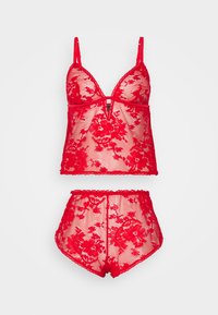 Completo di lingerie in pizzo rosso con un reggiseno trasparente decorato con motivi floreali e spalline regolabili, abbinato a pantaloni corti a vita alta.