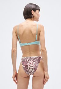 Μπικίνι δύο τεμαχίων: υφασματινό τοπ σε αποχρώσεις του aqua με ρυθμιζόμενες τιράντες, συνδυασμένο με κάτω μέρος με σχέδια σε κρεμ και μπορντό, με λουλουδάτα και αφηρημένα μοτίβα.