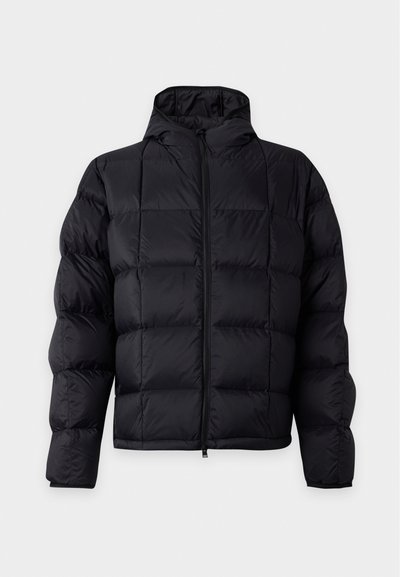 Veste matelassée noire avec un matelassage horizontal et vertical, fermeture éclair à l'avant, manches longues et capuche sur un fond clair uni.