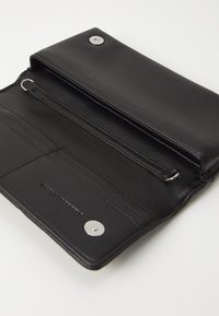 Portafoglio in pelle nera con una superficie liscia. Presenta una chiusura a scatto, un compartimento con zip e diversi slot per carte, evidenziando linee pulite.
