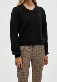 Svart knäppbar cardigan med en mjuk textur, med rundad krage, långa ärmar och sex runda knappar framtill.