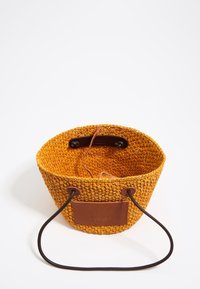 Woven round basket in bright orange with a textured surface. Features brown leather accents and drawstring closure for secure fastening.