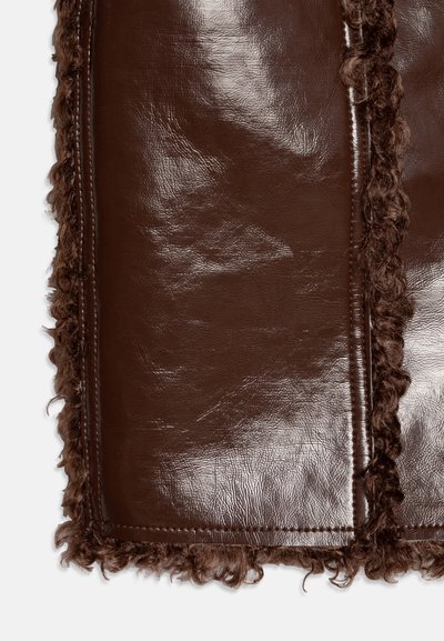 Brown leather item featuring a smooth surface with a textured, curly fur trim along the edges. Clean stitching visible along the seams.