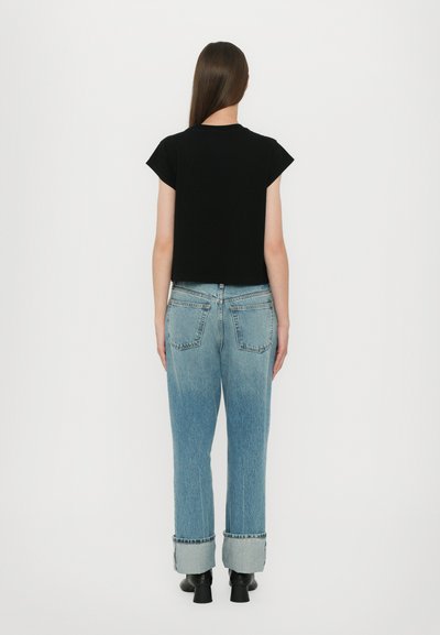 Black cropped t-shirt with short sleeves paired with light blue high-waisted jeans, rolled cuffs, and black ankle boots. Simple design.